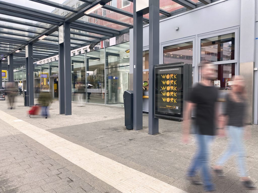 Ingang Eindhoven station gezien van bus opstapplaats met reclame bord McDonalds